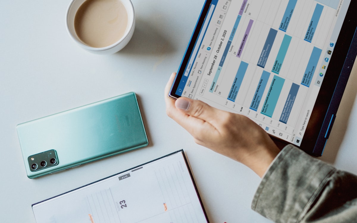 Mesa com celular e tablet exibindo calendário e agenda para agendar mensagens