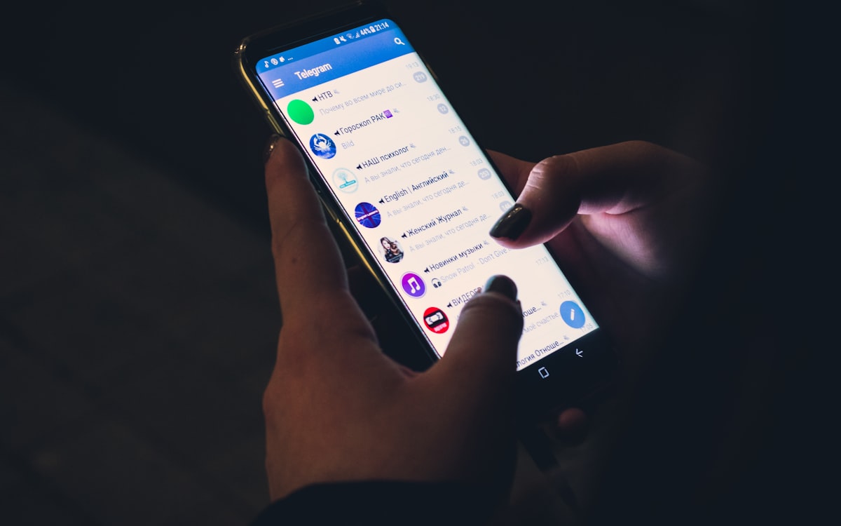 Pessoa segurando celular com aplicativo de mensagens aberto, mostrando perfil e nome de usuário no WhatsApp